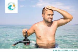 a man stands waist deep in water with a snorkel mask