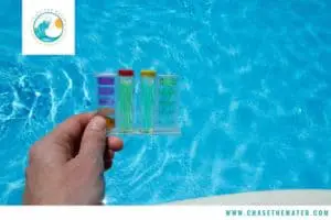a swimmer tests pool water using test equipment